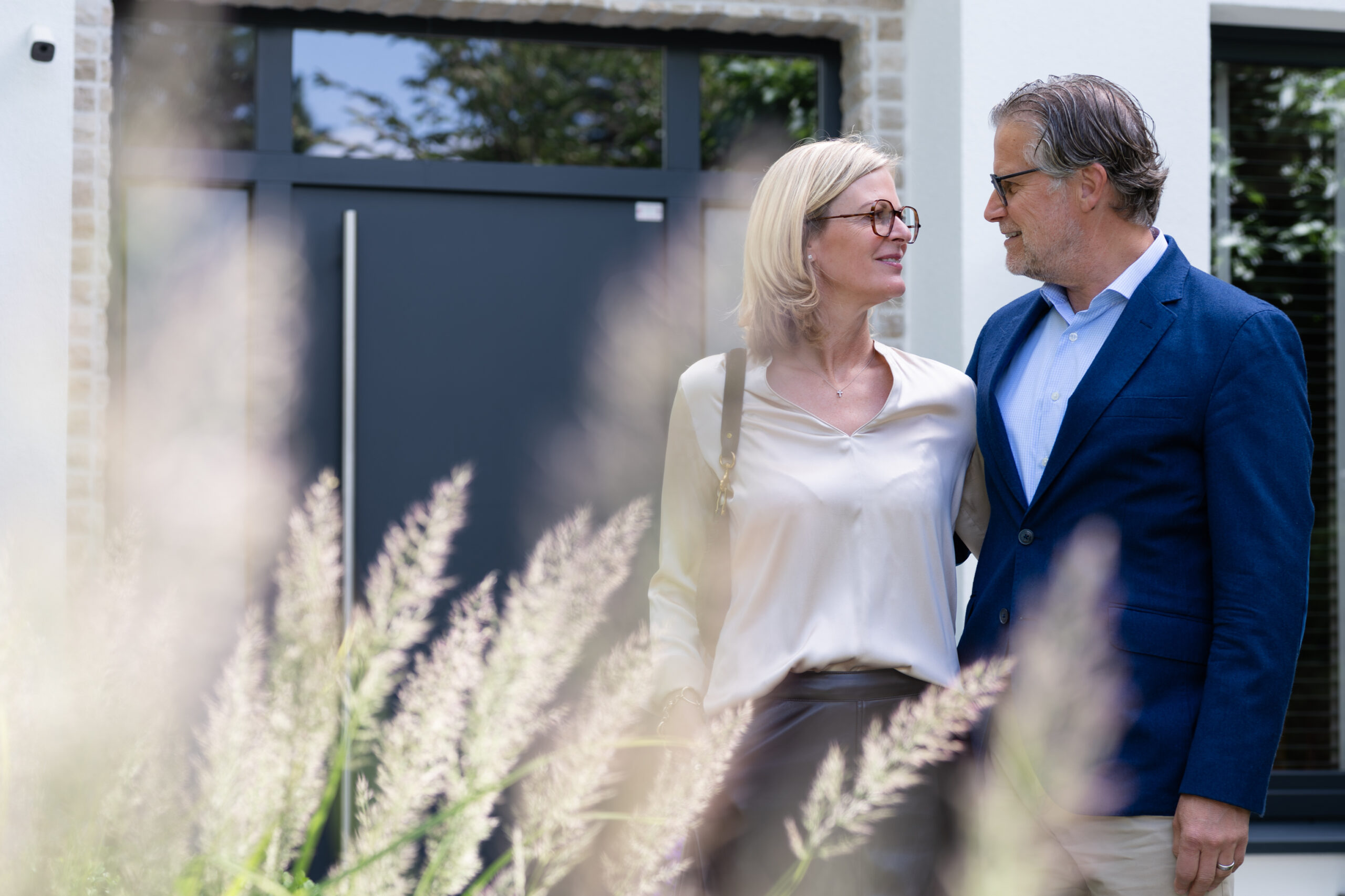 Ein Paar sieht sich vor dem Haus an, Gräser unscharf im Vordergrund