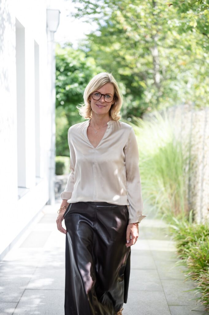 Corinna Starcke geht allein einen Gartenweg entlang