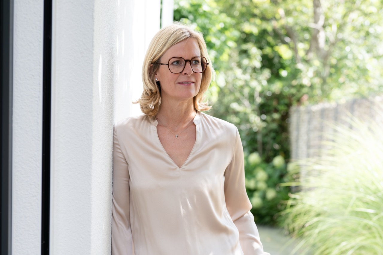 Corinna Starcke an der Hauswand, nachdenklicher Blick zur Seite Corinna Starcke lehnt an einer Hauswand und schaut zur Seite