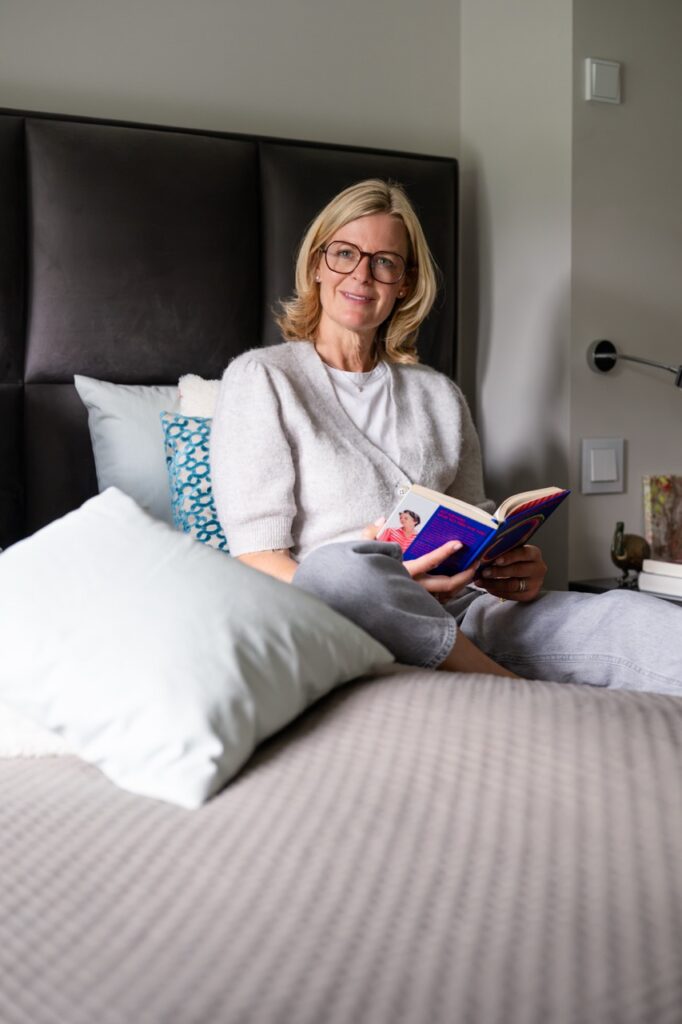 Corinna Starcke sitzt im Bett und liest in einem Buch