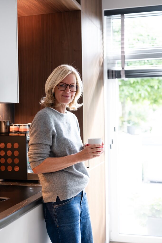 Corinna Starcke steht mit einer Tasse in der Küche am Fenster